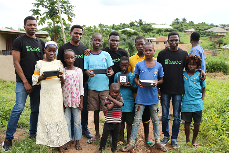 Olugbenga Olubanjo (back row, second from left) poses for a photo with members of the Reeddi team, local community members and his startup's power-providing capsules during an August pilot project in Ayegun, Nigeria (photo courtesy of Olugbenga Olubanjo)