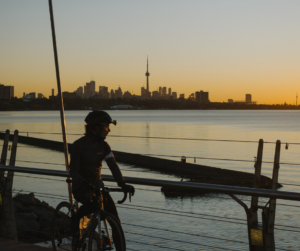Cyclist watches Toronto skyline at sunset.