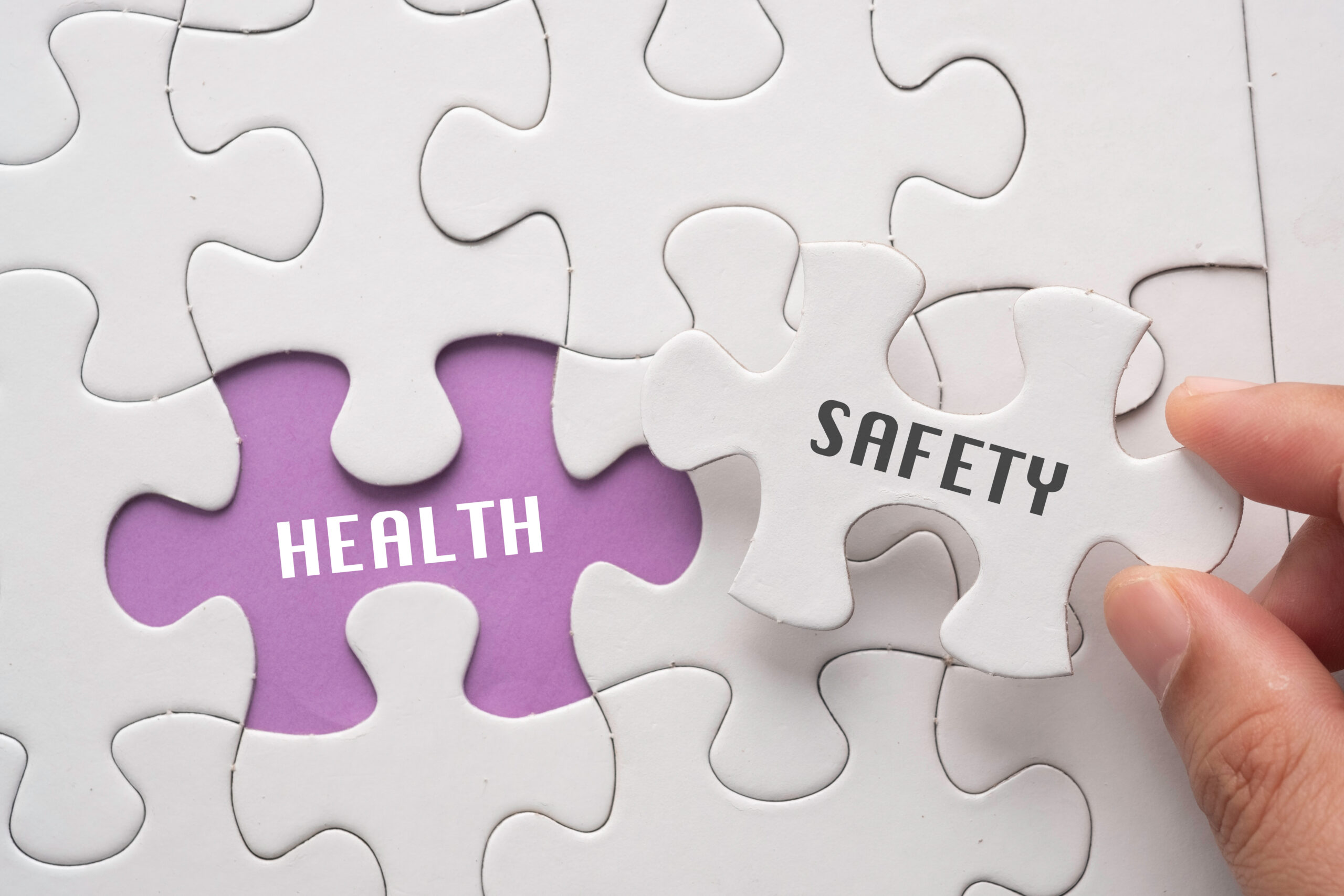 Hand hold piece of puzzle written SAFETY revealing word HEALTH.