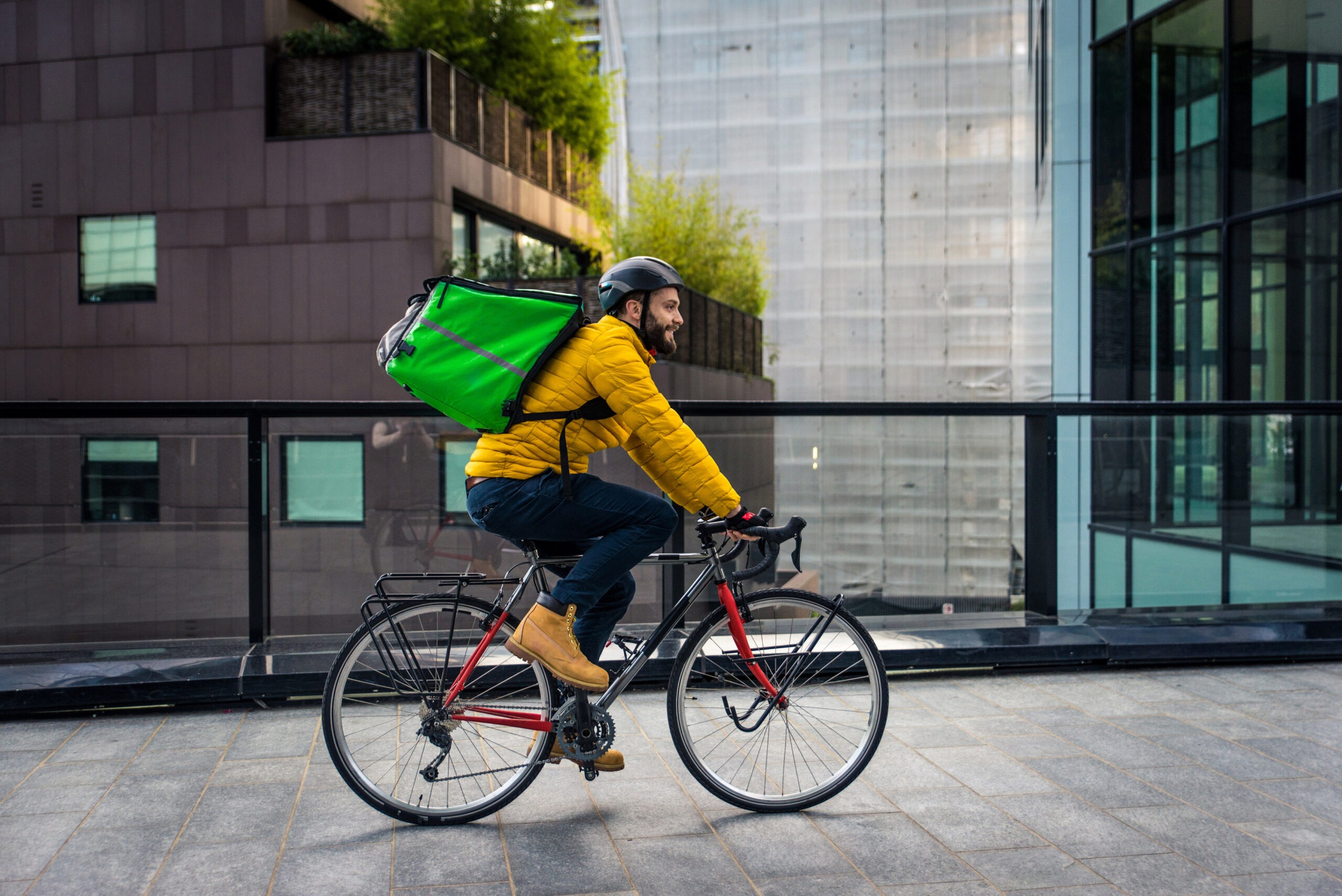 Food delivery rider on his bicycle. Image of a middle age man at work in the city center. Delivering pizza and burgers at home with the thermal backpack