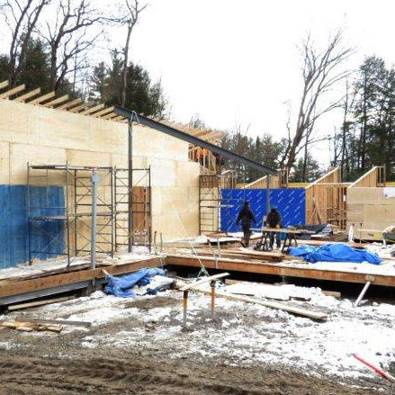 A November 2020 view of the MacGillivray Common Room (centre with workers) and washrooms structure (left). U of T Survey Camp at Gull Lake, near Minden, Ont., began construction of its new facilities, including the HCAT Bunkhouse, during spring 2020. (Photo courtesy of Wayne Bennett, CivE 6T9)