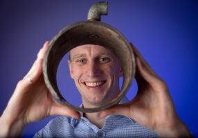Assistant Professor David Taylor with a segment of pipe, related to his research on water distribution networks.