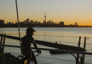 Cyclist watches Toronto skyline at sunset.